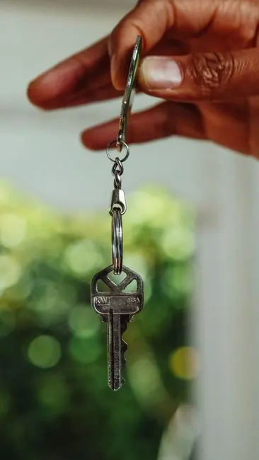 Main qui tend une clé de logement au bout d'un anneau