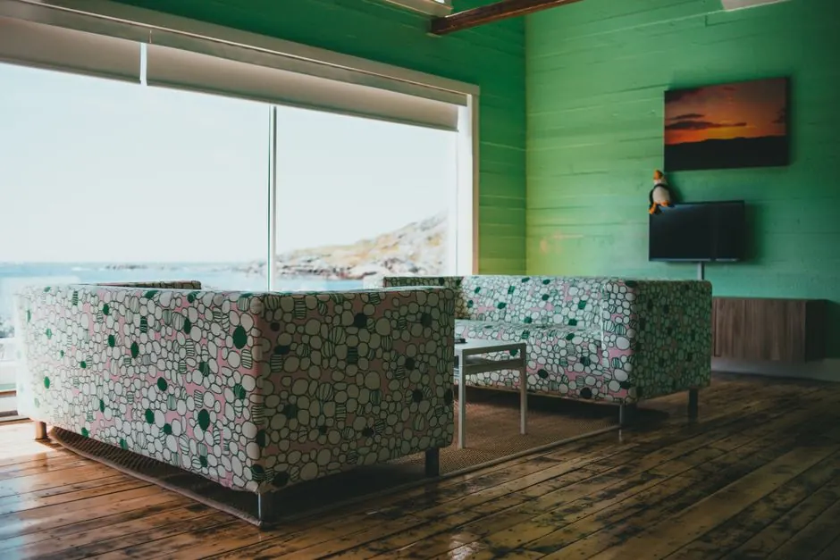 Salon avec deux canapés à motifs et une grande baie vitrée ouverte sur la mer